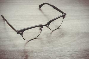 Eyeglasses Glasses with Black Frame Fashion Vintage Style on Wood Desk Background photo