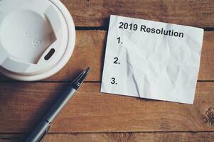Resolution for 2019 word on paper with pen and coffee cup on wooden table. Business concept. photo