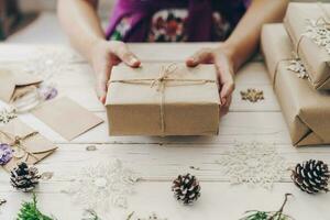 Close up of hands woman present gift box on wooden table with xmas decoration. photo