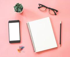 Flat lay mockup design of workspace desk with blank notebook, smartphone, stationery on pink pastel color with copy space photo