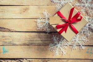 Christmas gift boxes placed and white snowflakes on wooden planks with space. photo