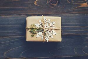 String or twine tied in a bow on kraft paper. Above gift box on wood with space. photo