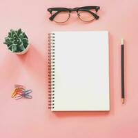 Flat lay mockup design of workspace desk with blank notebook, smartphone, coffee, stationery on pink pastel color with copy space photo