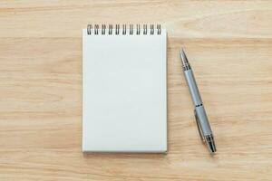 Top view of blank notebook with pen and natural light on wooden table. photo