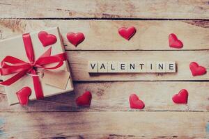regalo caja y rojo corazón con de madera texto enamorado en madera mesa antecedentes. foto