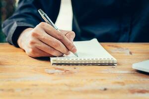 Hand business man writing notebook on wood table in coffee shop. photo