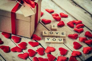 regalo caja y rojo corazón con de madera texto para yo amor usted en madera mesa antecedentes. foto