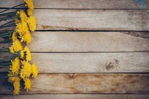 Yellow flowers of bouquet, top view on wooden background texture with copy space photo