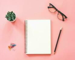 Flat lay mockup design of workspace desk with blank notebook, smartphone, coffee, stationery on pink pastel color with copy space photo