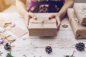 Woman hand holding beautiful Christmas gift box at table photo