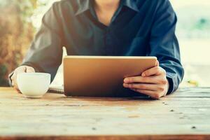 Man using tablet on table in coffee shop with vintage toned filter. photo