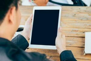 Business man hand holding tablet in coffee shop. photo