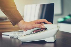 Business man using telephone and laptop in the office. Vintage toned. photo