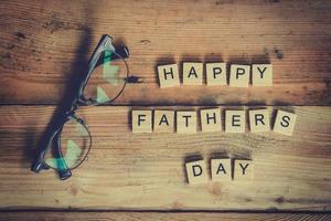 Happy father's day block with glasses on wood background. photo