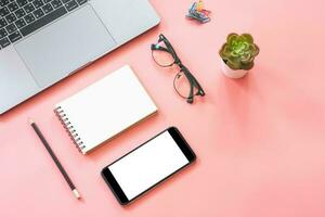 Flat lay design of workspace desk with laptop, blank notebook, smartphone, pencil, stationery with copy space background photo