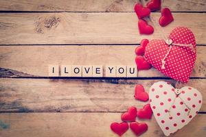 Heart fabric frame and wooden text I LOVE YOU on wooden table background.