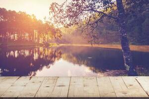 Empty wood table for product display and montage on pond water and sunrise with vintage toned. photo