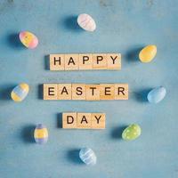 vistoso Pascua de Resurrección huevo y madera texto contento Pascua de Resurrección día en azul pastel color madera antecedentes con espacio. foto