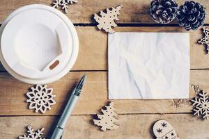 Top view cup coffee and pen, empty paper on wood with christmas decoration for New year concept. photo