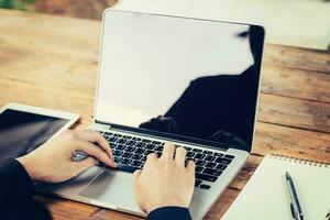 Business man hand using laptop on table in coffee shop with vintage toned filter. photo