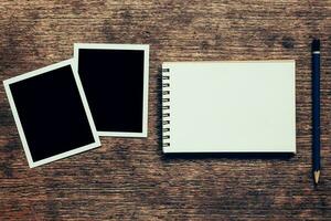 Note book and Photo frame on wood background.