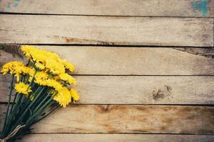 Yellow flowers of bouquet, top view on wooden background texture with copy space photo