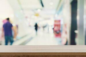 Empty wooden table top with blurred modern shopping mall background for product display and montage. photo