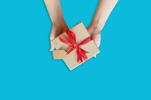 top view hand woman holding brown gift box for new year on blue pastel color background with space. photo