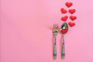 cuchillería conjunto y rojo corazón en rosado pastel color con espacio para texto. foto