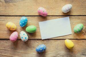 vistoso Pascua de Resurrección huevo y papel tarjeta en madera antecedentes con espacio. foto