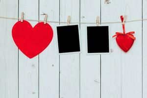 Two photo frame blank and red heart hanging on white wood background with space