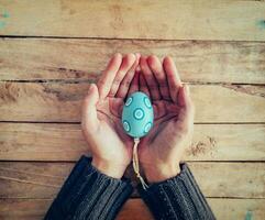 Close up hand woman holding and person easter eggs on wood table background. photo