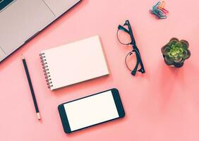 Flat lay design of workspace desk with laptop, blank notebook, smartphone, pencil, stationery with copy space background photo