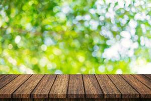 Empty wooden table and abstract blurred green bokeh leaves background texture, display montage with copy space. photo