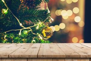 Empty wood table and christmas pine cones hanging from Christmas tree with display montage for product. photo