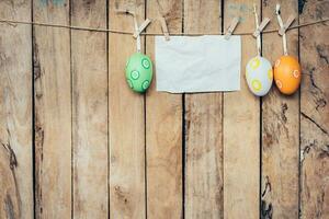 easter egg and blank paper for label hanging on wood background with space. photo