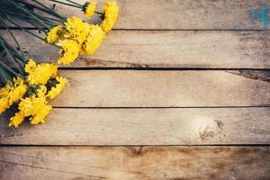 Yellow flowers of bouquet, top view on wooden background texture with copy space photo