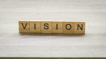 Wooden block with vision massage on wood table background. photo