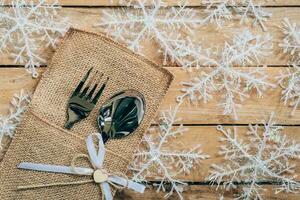 Navidad mesa sitio ajuste y cubiertos, copos de nieve en de madera antecedentes con espacio. foto