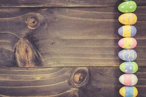 Colorful easter eggs on plank wooden background with space. photo