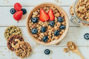 bowl of granola with fresh berries, strawberry on wood table. photo