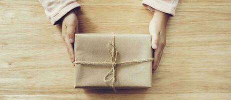 panorama of girl hand holding gift box on wood table background photo