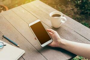 Woman hand holding phone with blank copy space screen for your advertising. Hand woman using phone in coffee shop. photo