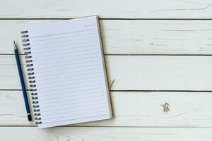 Open notebook with blank pages and pencil on wood table photo