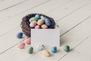 Easter egg and nest with blank paper on wood table background, copy space. photo