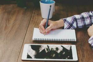 Business woman hand writing notebook on wood table. photo