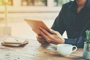 Asia business man holding tablet on table in coffee shop with vintage toned filter. photo