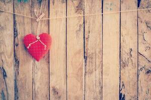 Heart fabric hanging on clothesline and wood background with space. photo