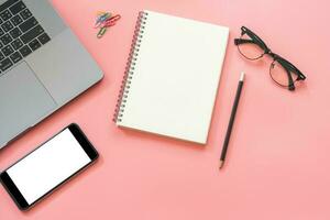 Flat lay design of workspace desk with laptop, blank notebook, smartphone, pencil, stationery with copy space background photo