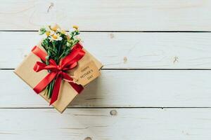 Brown gift box and flower on wood table present, mother's day concept. photo